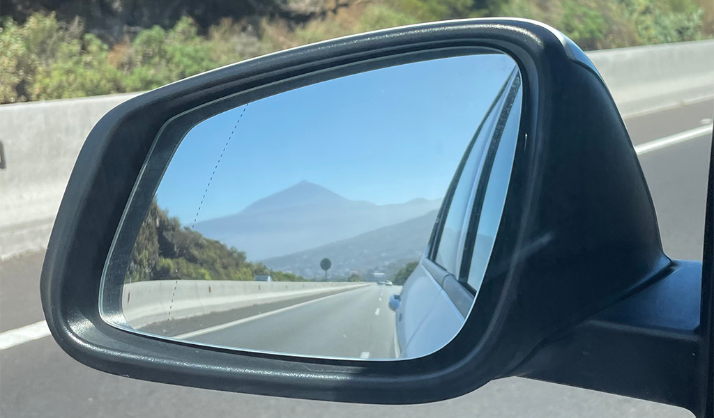 Reflejo del Teide en espejo retrovisor de un coche en carretera de Tenerife.
