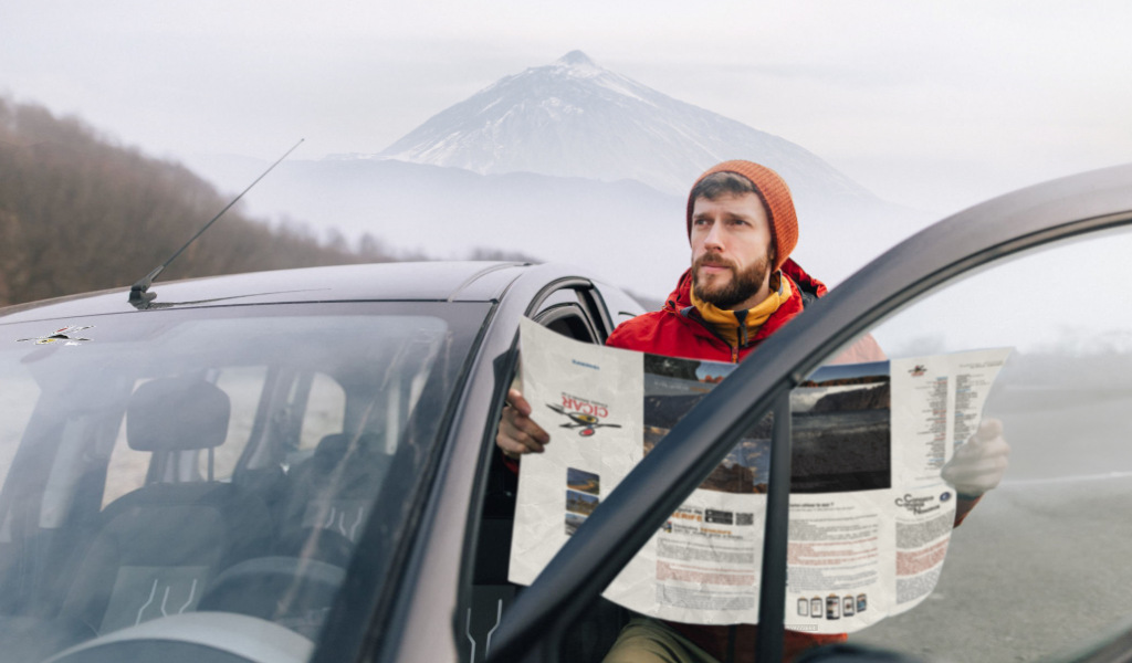 Hombre consulta un mapa junto a un coche con el Teide al fondo, Tenerife.