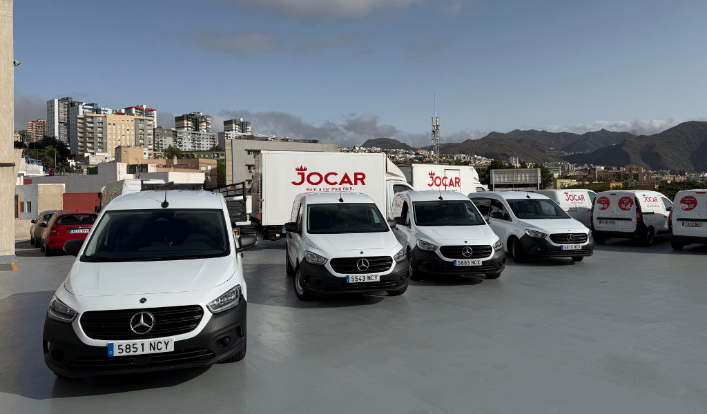 Furgonetas estacionadas de Jocar en Santa Cruz de Tenerife, con edificios y montañas al fondo.