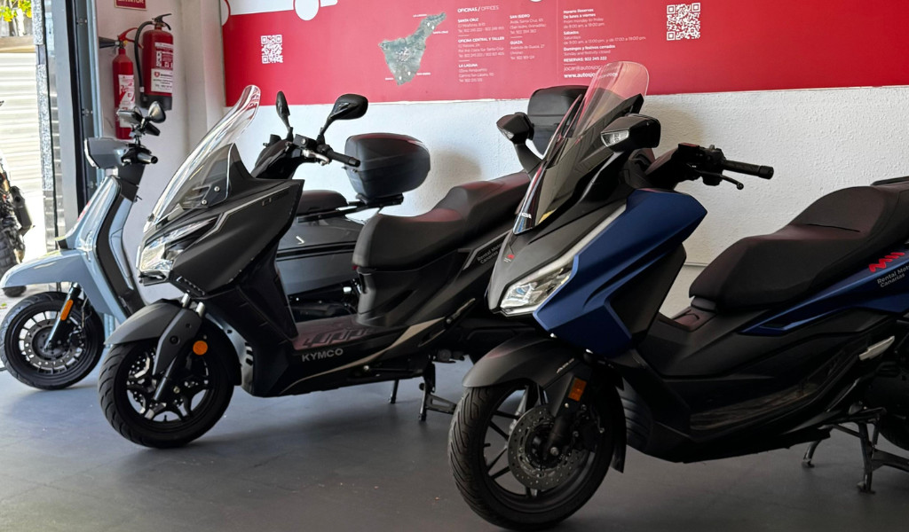 Motos Kymco en exposición, fondo con mapa de Tenerife y extintores.