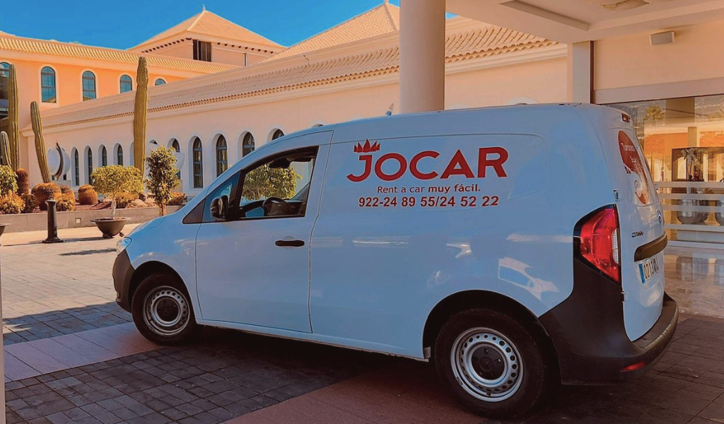 Furgoneta de alquiler Jocar estacionada frente a un edificio en Tenerife.
