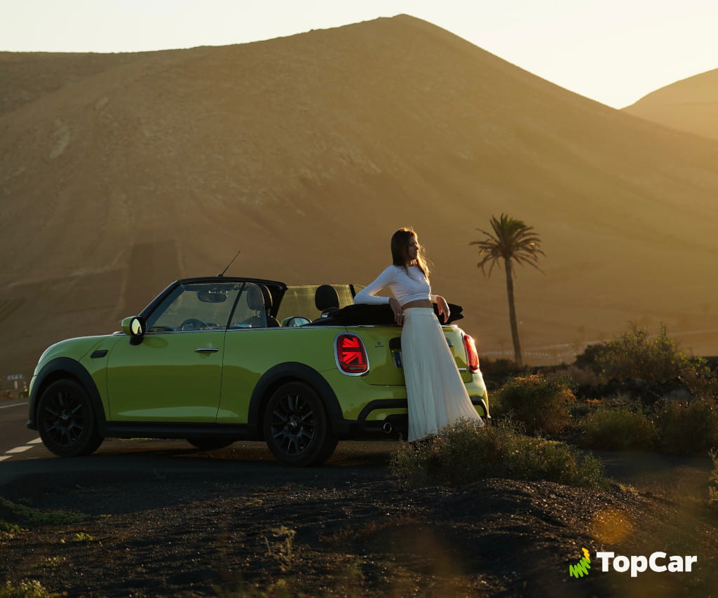 Coche descapotable verde con persona frente a paisaje montañoso en Tenerife.
