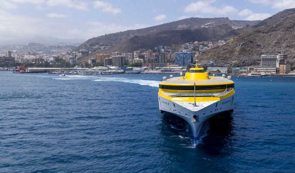 Ferry amarillo en el puerto de Santa Cruz de Tenerife con la ciudad de fondo.