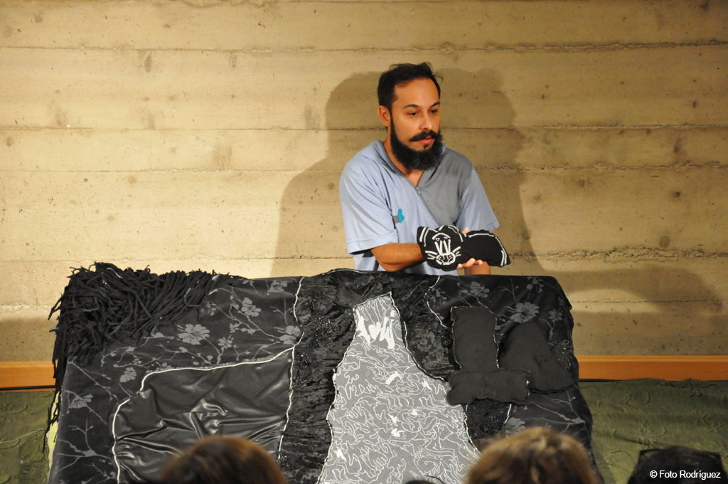 Persona con títeres blancos y negros en una obra de teatro en Tenerife.