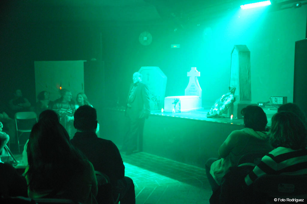 Escenario con ataúdes y personas sentadas en teatro de Tenerife.