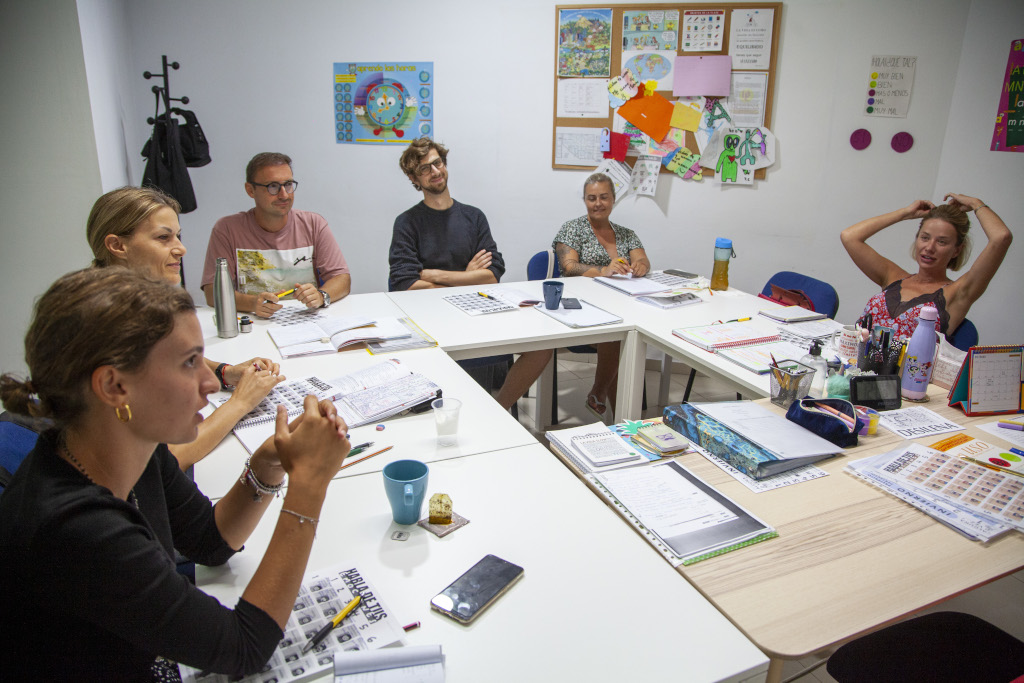 Grupo de personas en mesa de trabajo en aula de escuela en Tenerife.