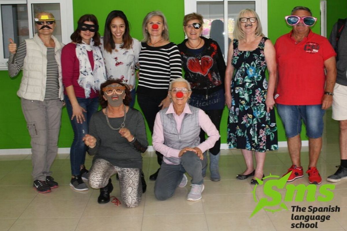 Grupo de personas con disfraces y pelucas en frontis de SMS The Spanish Language School en Tenerife.