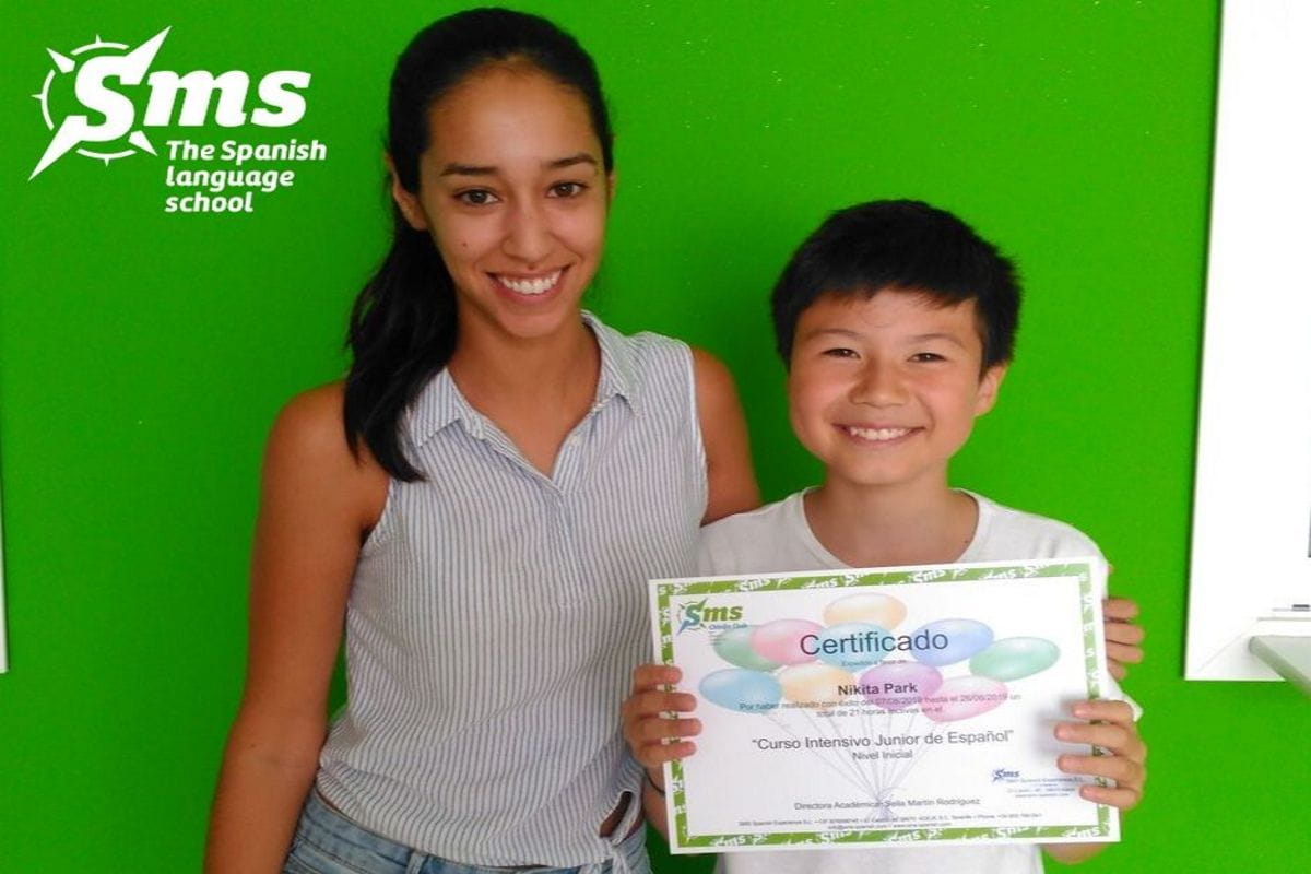 Persona joven con certificado Curso Intensivo Junior de Español en Tenerife. Logo de SMS.