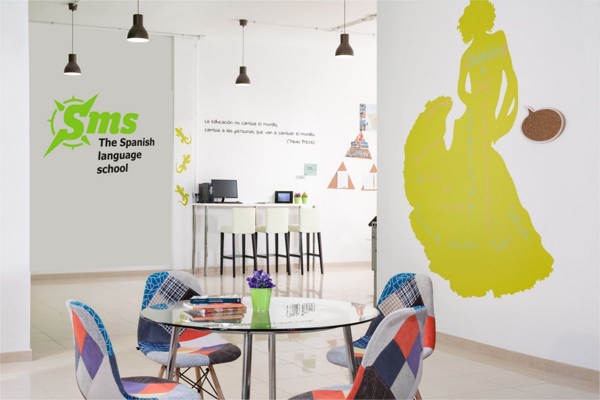 Aula de escuela de idiomas en Tenerife con sillas coloridas y lema en la pared.