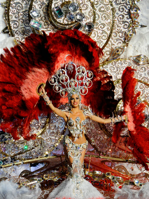 Comparsa de carnaval en Tenerife con traje brillante y grandes plumas rojas.
