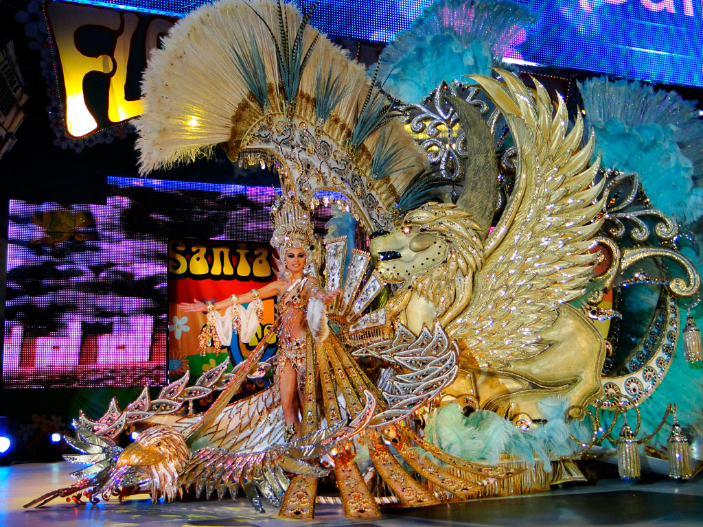 Personaje en traje festivo dorado con adornos de plumas y león alado en Santa Cruz de Tenerife.