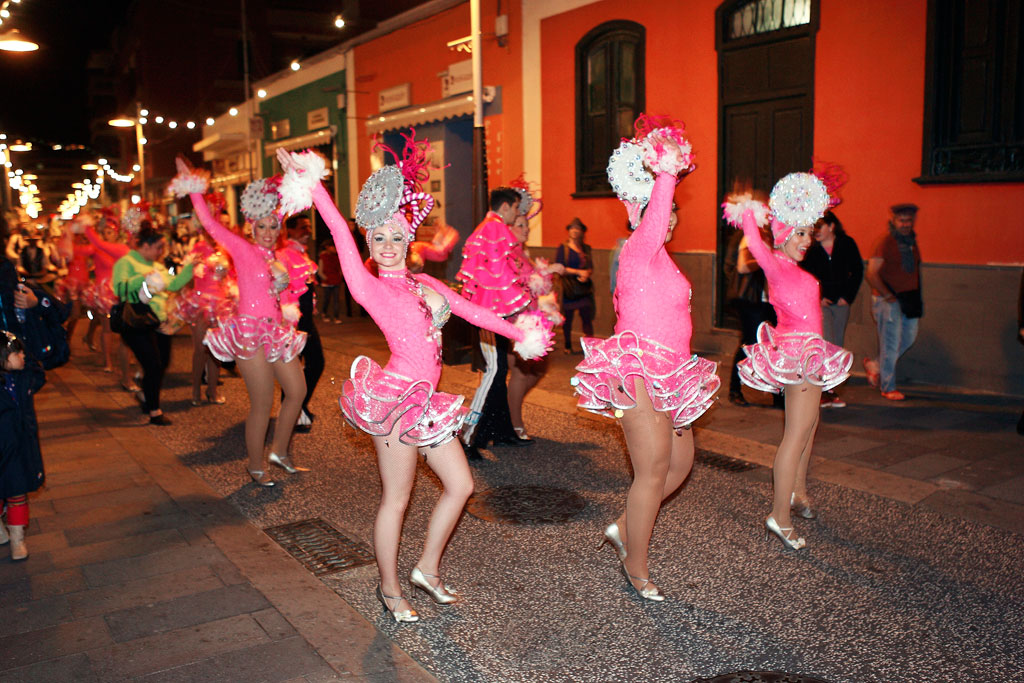 Bailarinas con trajes rosas desfilan en un carnaval nocturno en Tenerife.