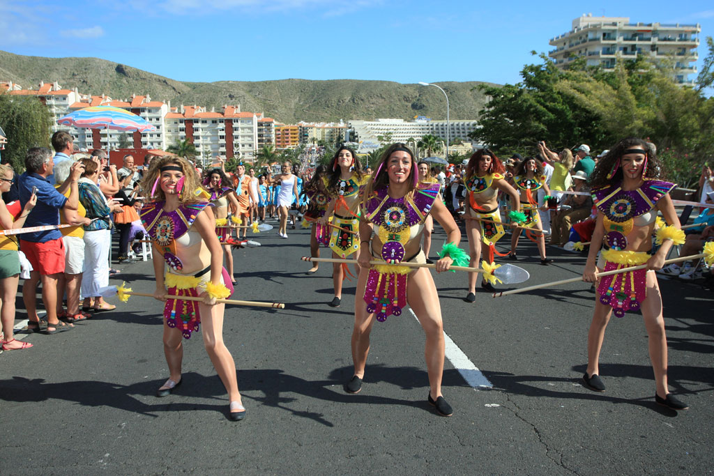 Personas disfrazadas bailan en un desfile en la calle principal de Los Cristianos, Tenerife.