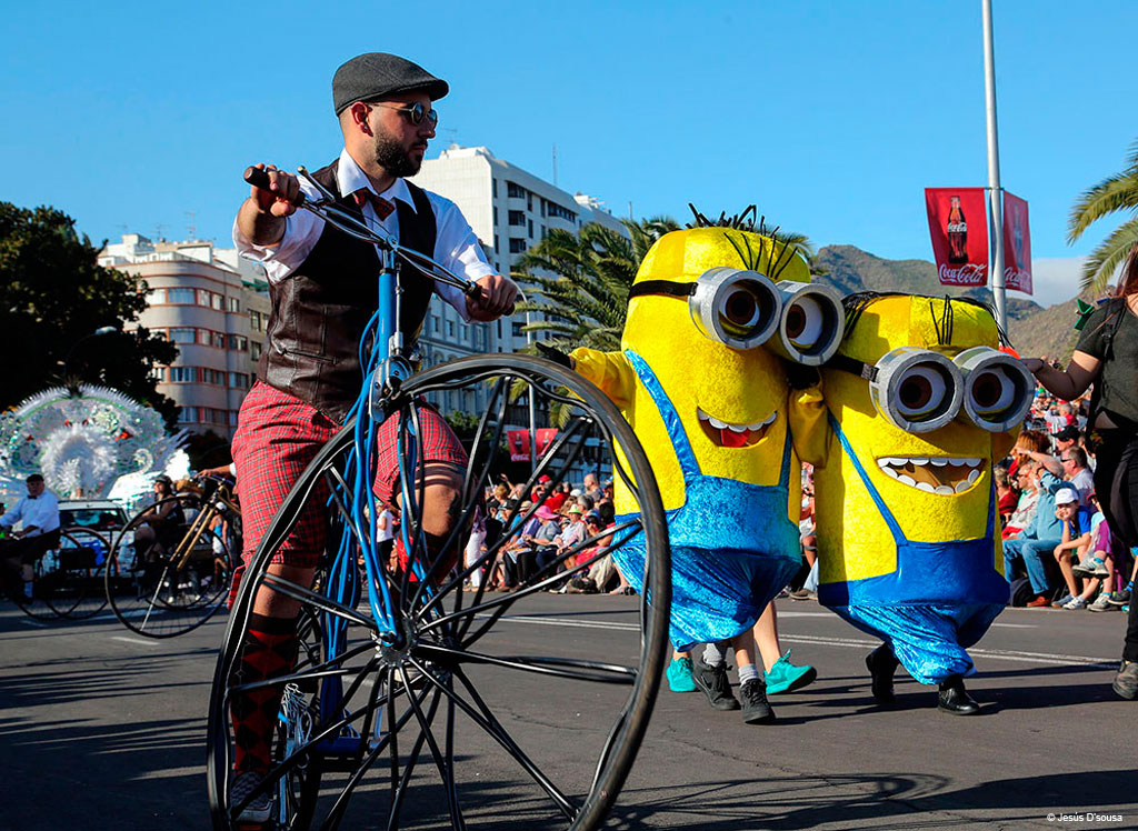 Desfile con personas disfrazadas de personajes amarillos y ciclista en bicicleta antigua en Tenerife.
