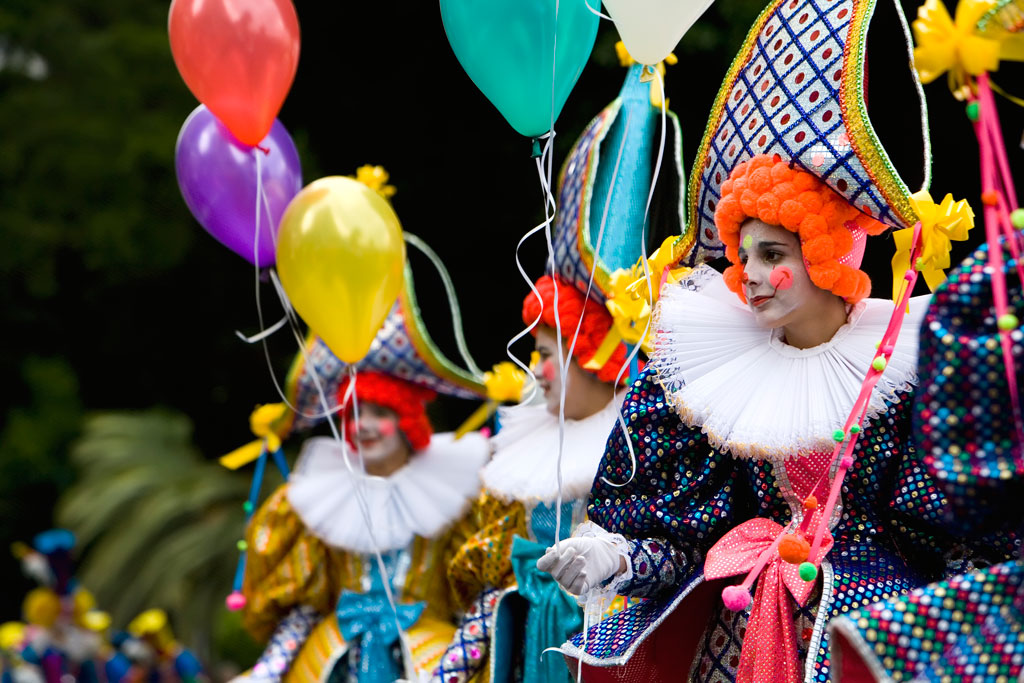 Personas vestidas de mimos con globos de colores en un desfile en Tenerife.