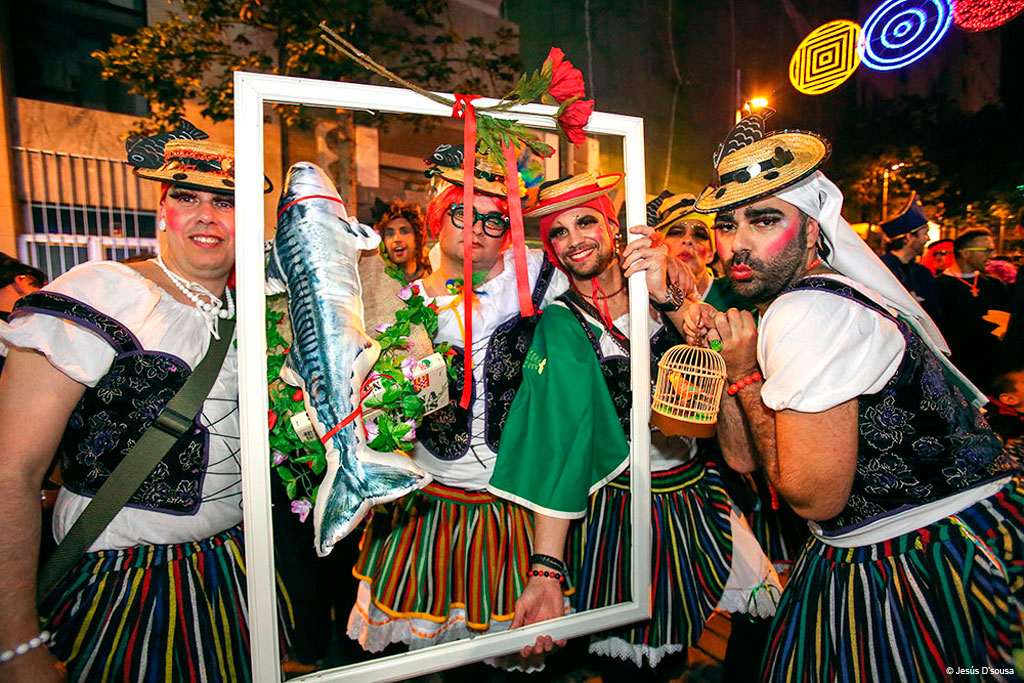 Grupo en carnaval de Tenerife con disfraces coloridos y un marco decorado.