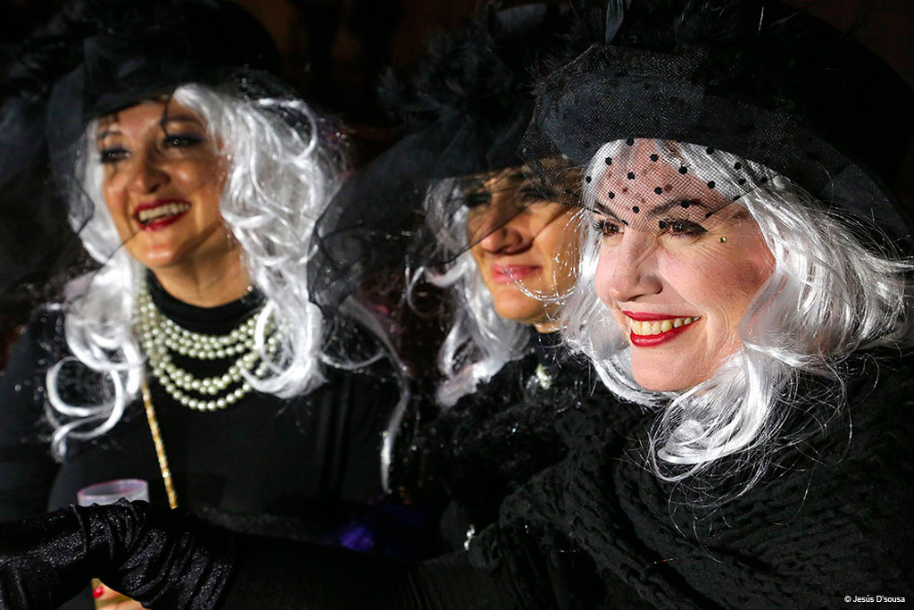 Personas disfrazadas con pelucas blancas y sombreros negros en el carnaval de Tenerife.