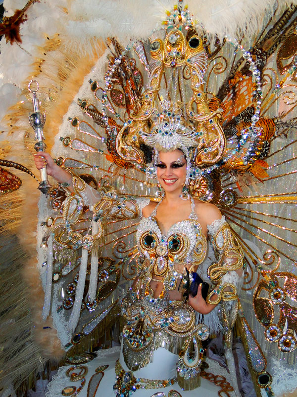 Persona en traje colorido y elaborado del Carnaval de Tenerife, sosteniendo un cetro.