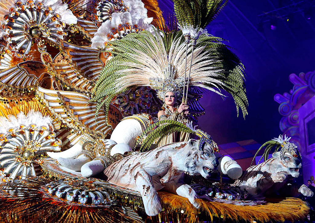 Carnaval en Tenerife con persona en carroza adornada con plumas y figuras de animales.
