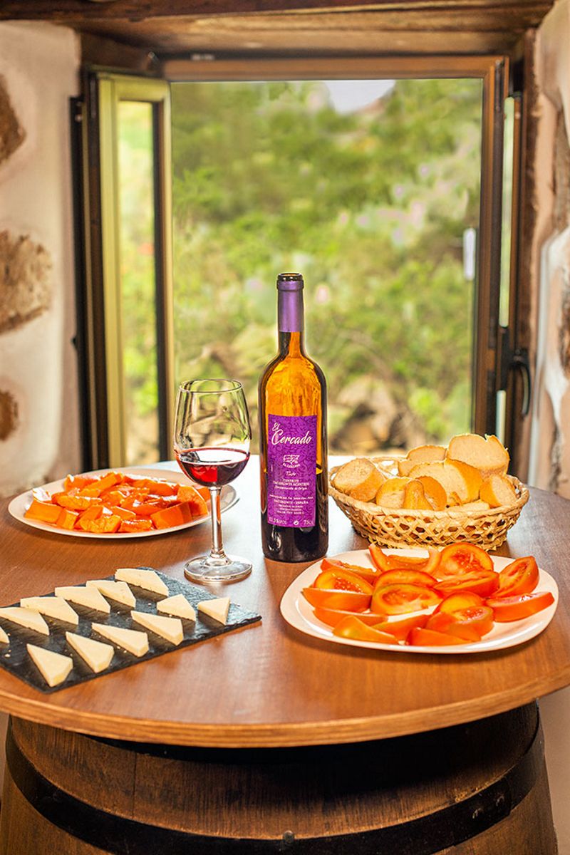 Botella de vino El Cercado y aperitivos sobre mesa en Tenerife.