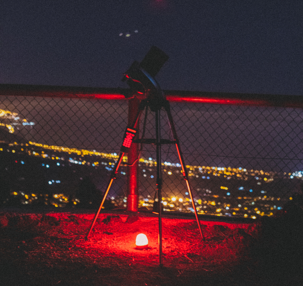 Telescopio en mirador con luces urbanas nocturnas en Tenerife.