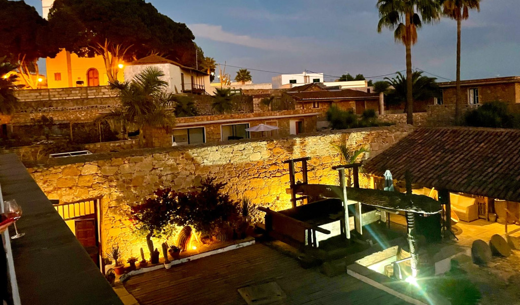 Patio iluminado con murallas de piedra y vegetación en una casa en Tenerife.