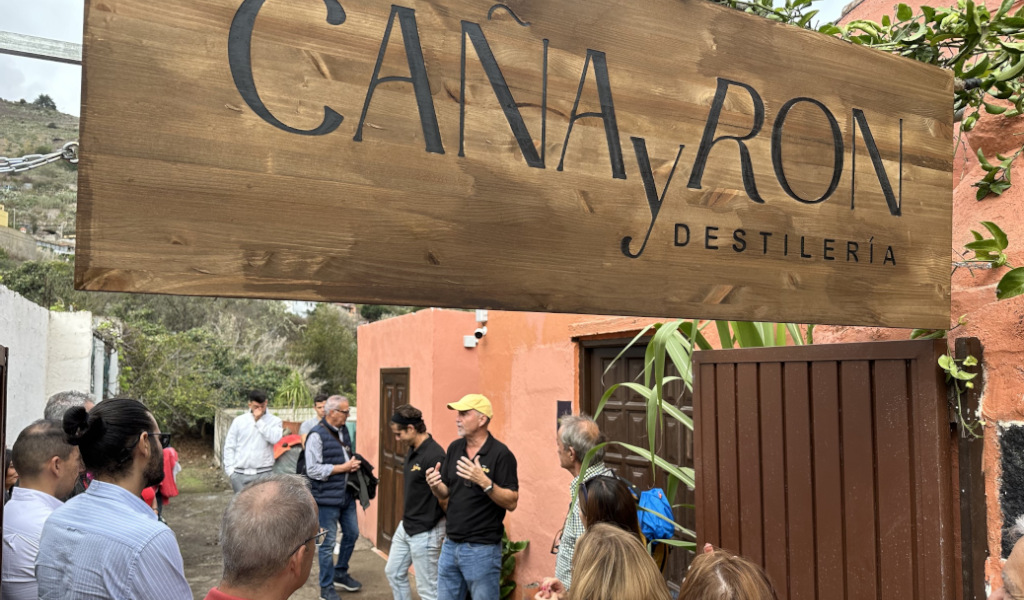 Personas reunidas bajo cartel CAÑA y RON DESTILERÍA en Tenerife.