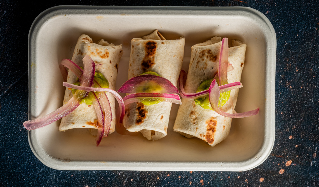 Tres burritos con cebolla roja y salsa verde en un plato rectangular en Tenerife.
