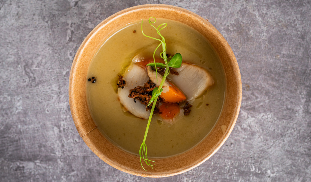 Sopa cremosa con verduras y brotes verdes en un tazón sobre mesa de piedra en Tenerife.