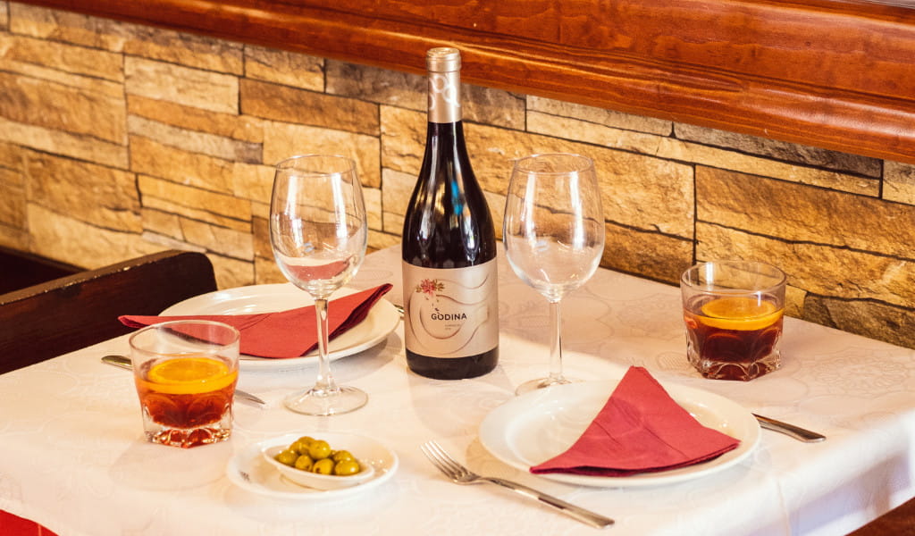 Mesa en restaurante de Tenerife con copas, botella de vino Gónda y vasos con bebidas.