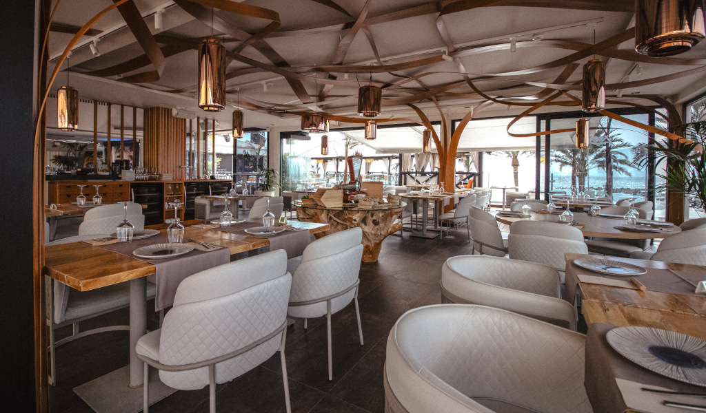 Restaurante elegante con mesas preparadas en Tenerife, vista al exterior con palmeras.