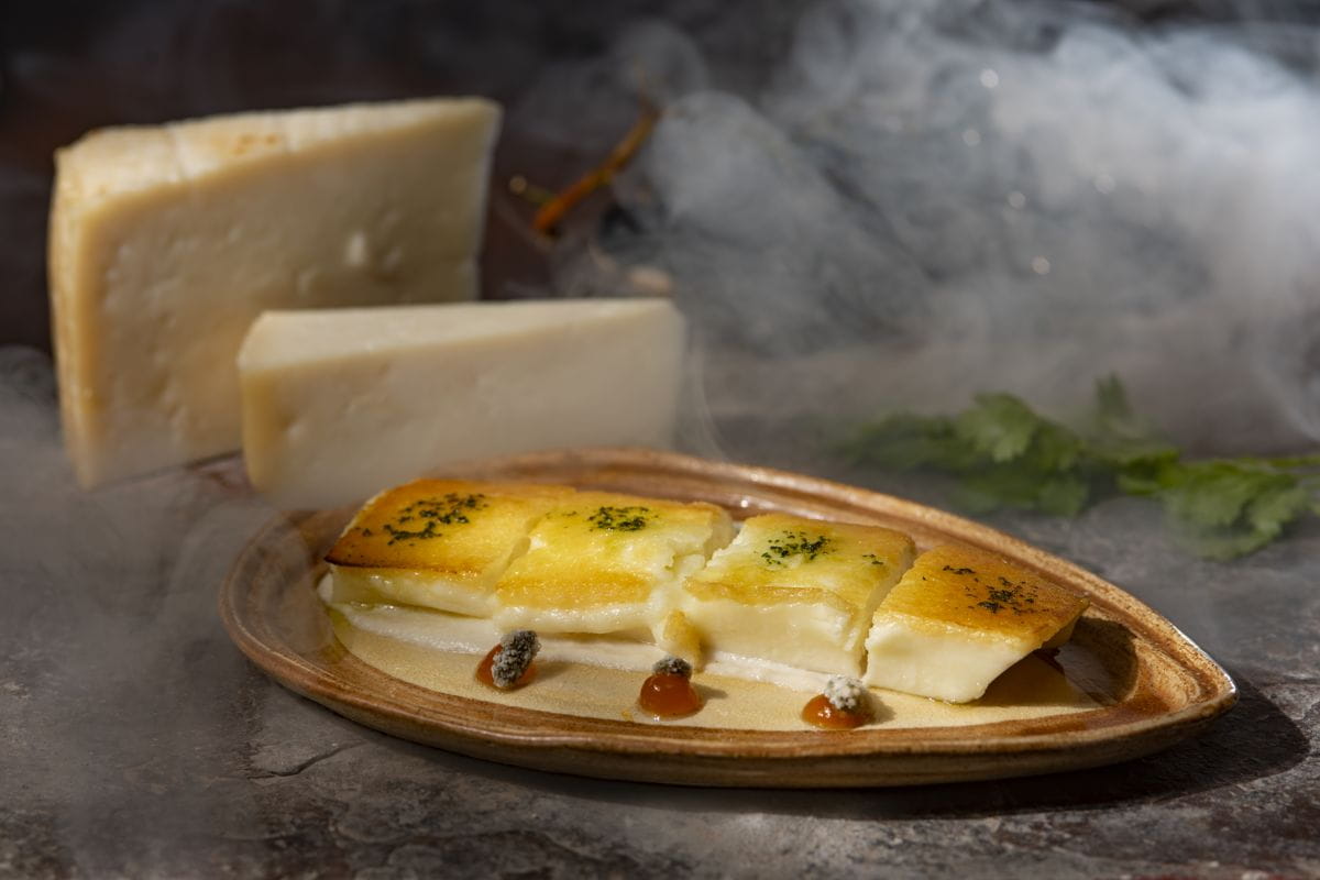 Queso asado con mermelada en un plato con fondo de humo en Tenerife.