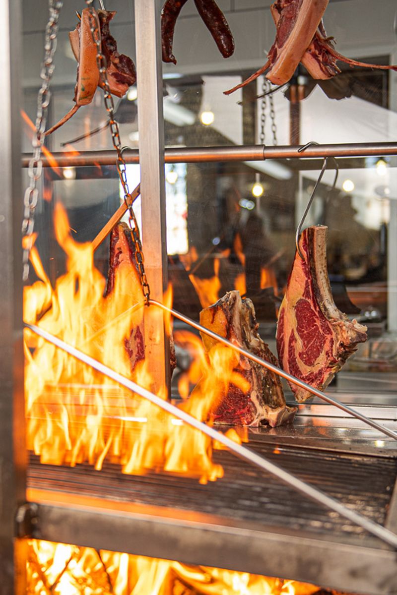 Carne asándose en parrilla con fuego intenso en Tenerife.