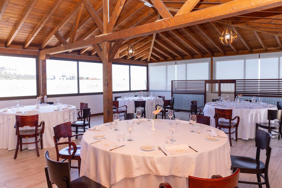 Comedor con mesas redondas y sillas de madera en restaurante de Tenerife.