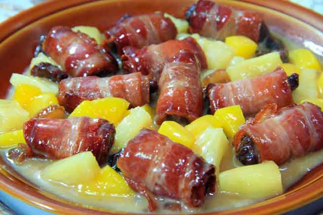 Plato de dátiles envueltos en bacon con trozos de piña y mango en Tenerife.