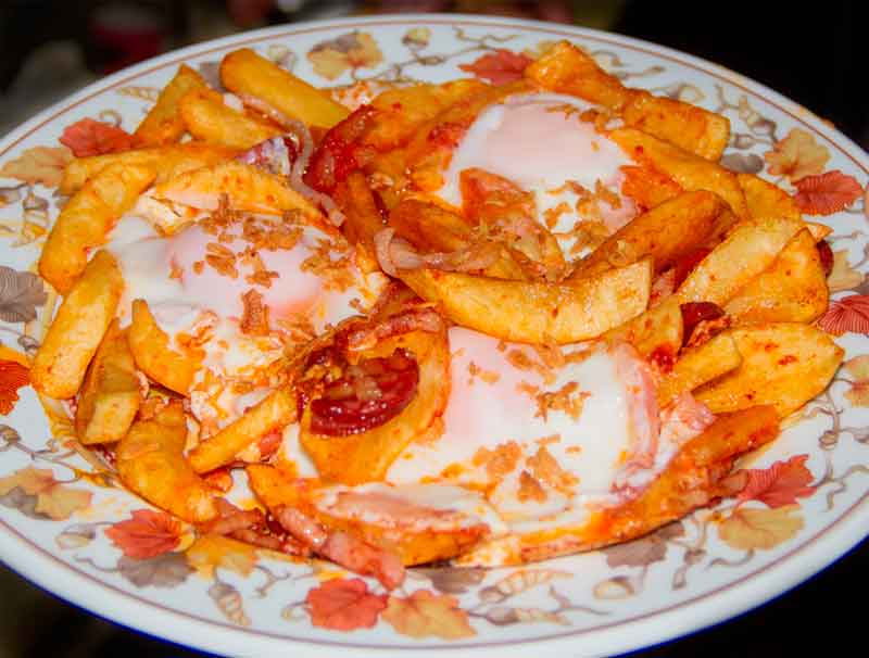 Papas fritas con huevos y chorizo en un plato decorado en Tenerife.
