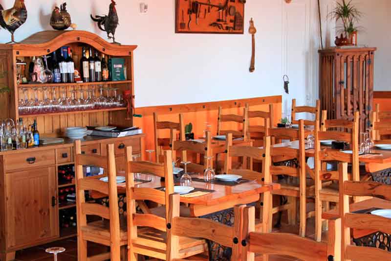 Restaurante en Tenerife con mesas y sillas de madera, y estantería con copas.