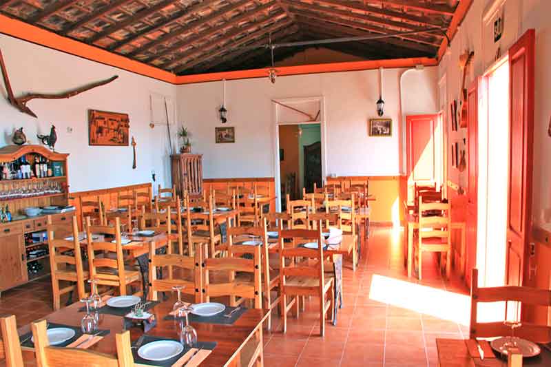 Restaurante de estilo rústico en Tenerife con mesas de madera y sillas dispuestas.