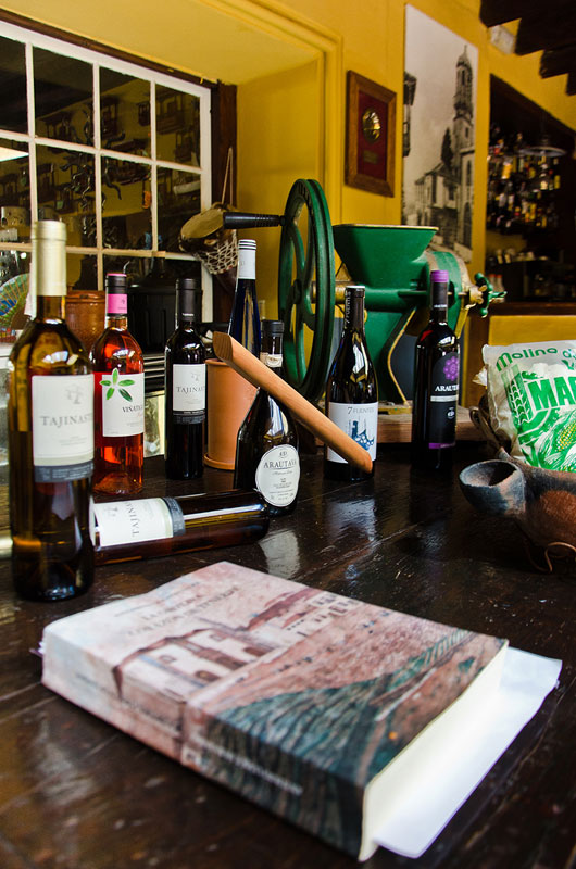Botellas de vino y café en una mesa en bodega de Tenerife. Texto visible: Tajinaste, ARARATLÁS.
