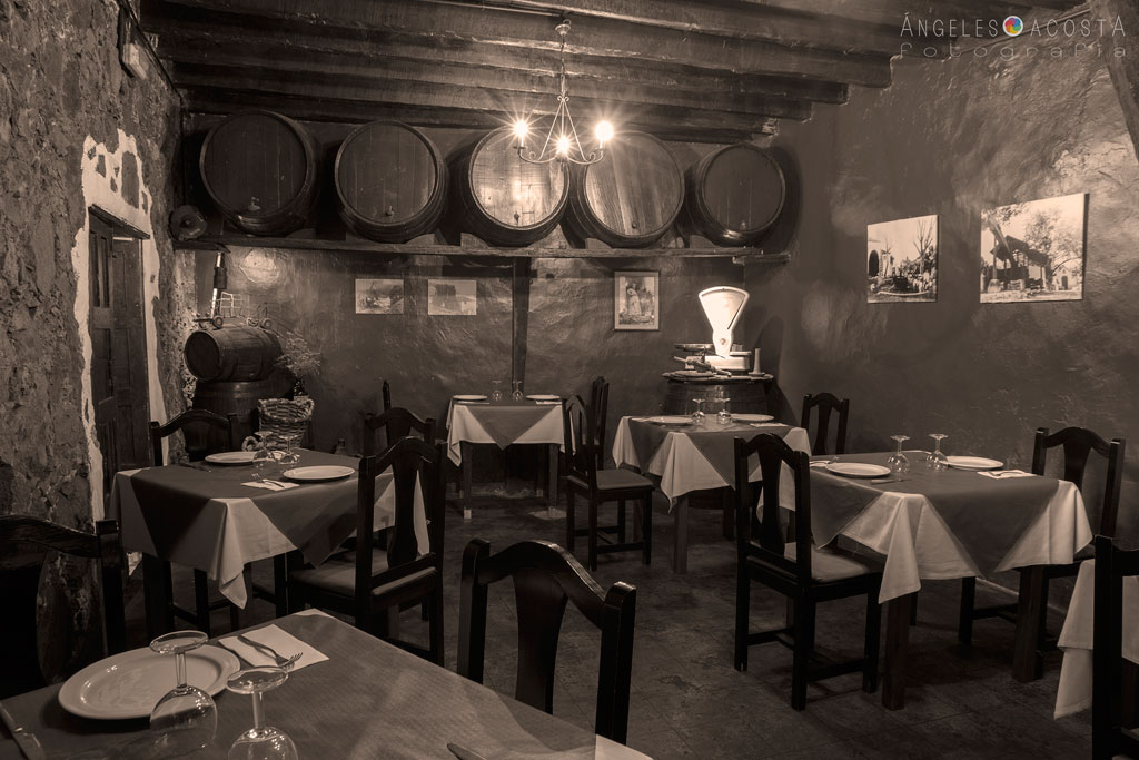 Interior de un restaurante rústico en Tenerife con mesas y barriles de madera.