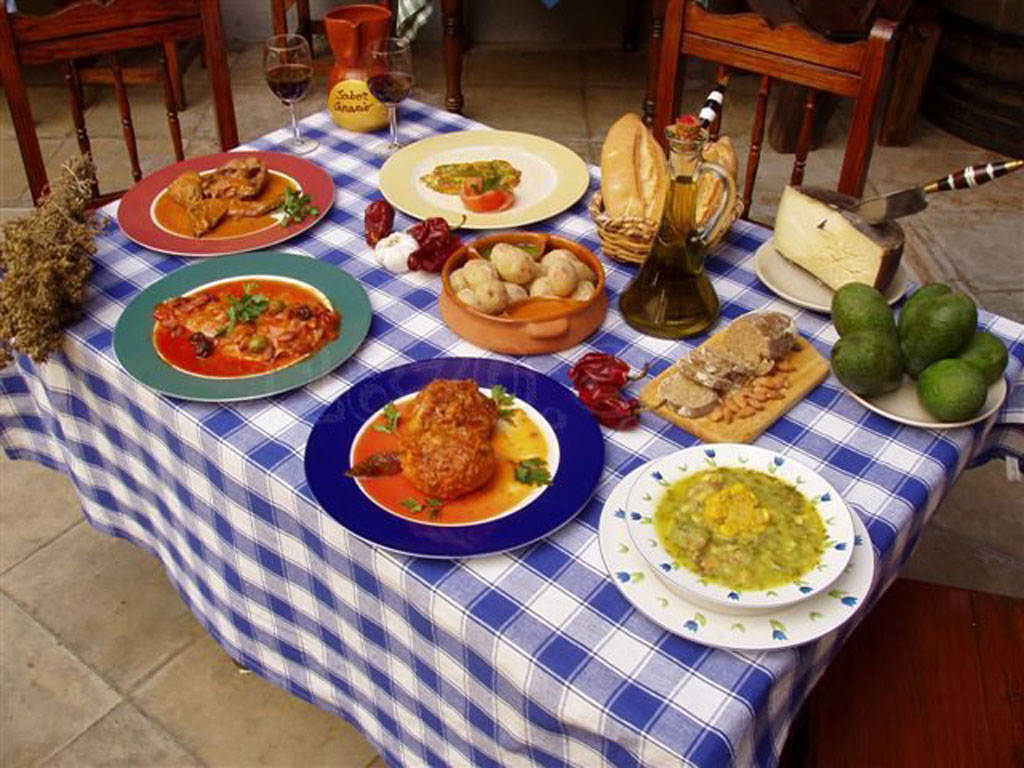 Mesa con platos típicos de Tenerife servidos, pan, queso y vino.