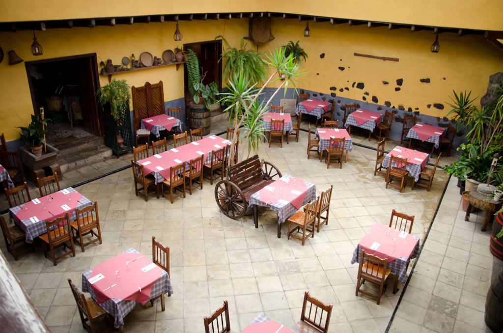 Mesas con manteles rojos y cuadros en un patio interior en Tenerife.