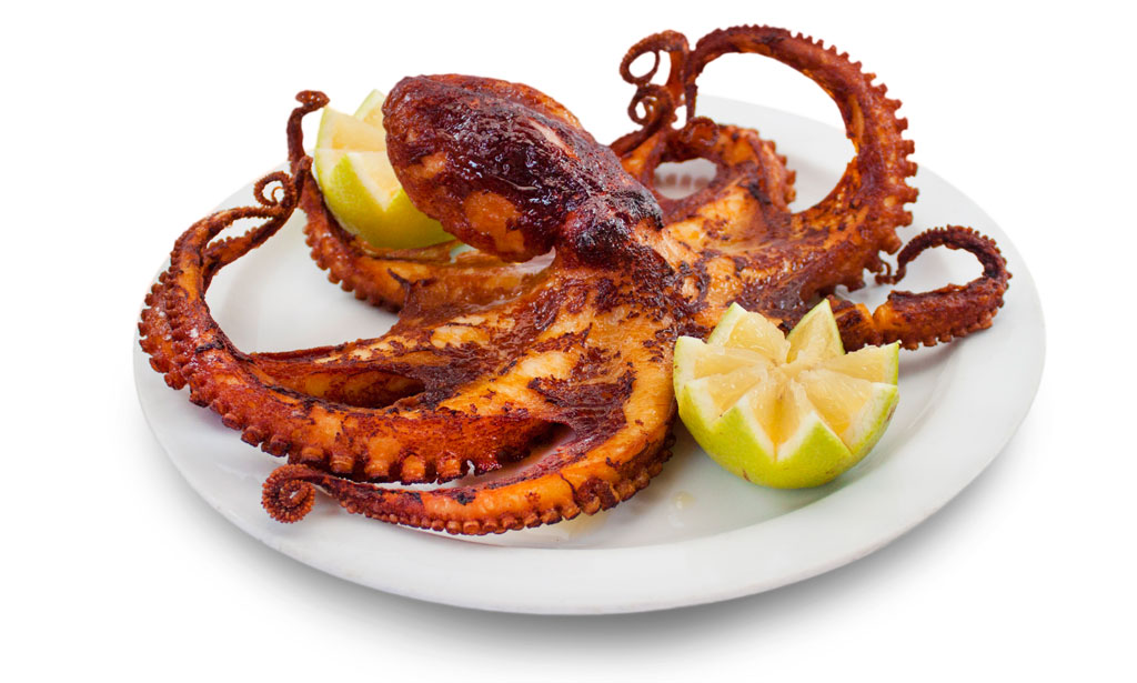Pulpo a la parrilla servido con rodajas de limón en un plato blanco en Tenerife.