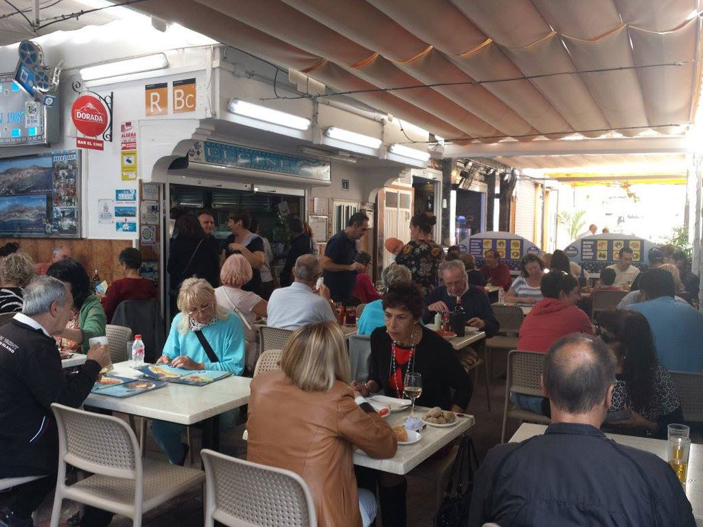 Personas cenando en restaurante en Tenerife, con menú y decoración visible.