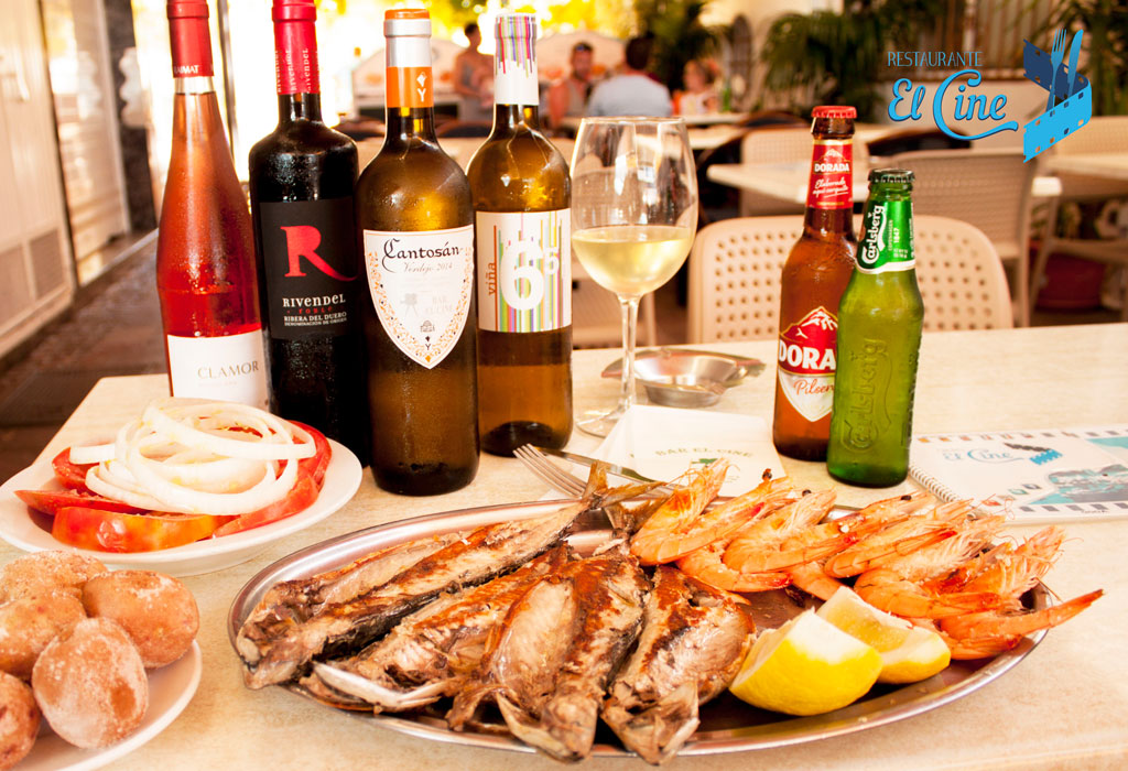 Plato de pescado y gambas con botellas de vino y cerveza en Restaurante El Cine, Tenerife.
