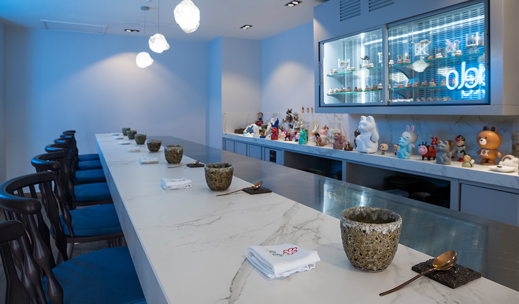 Barra de sushi con decoración de figuras y sillas azules en restaurante de Tenerife.