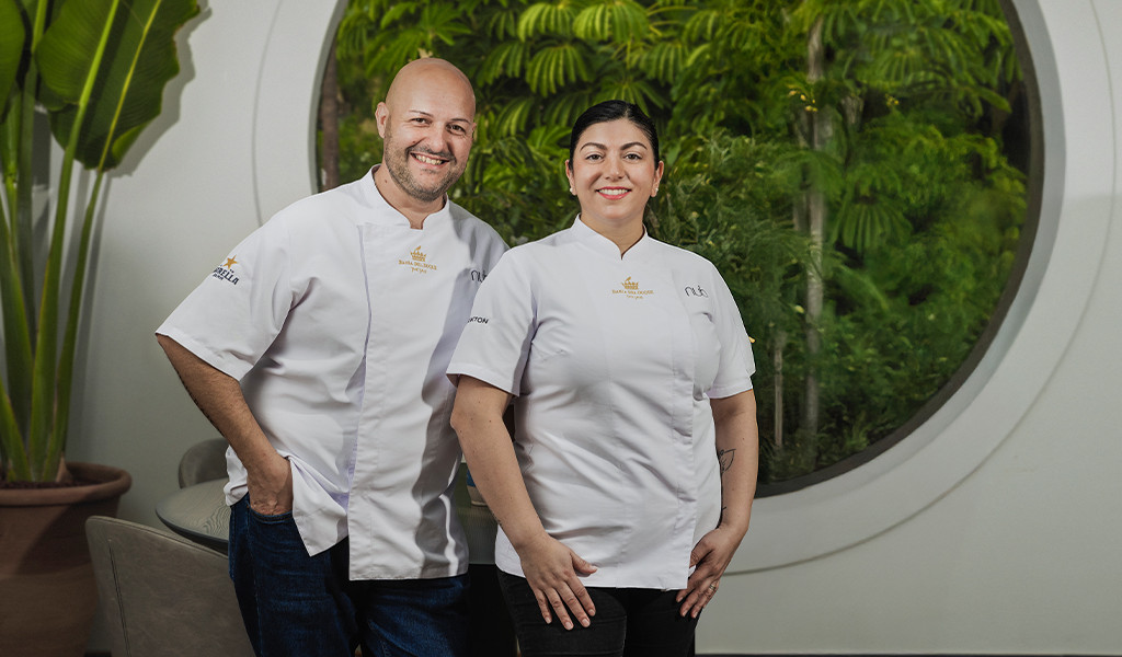 Dos chefs sonriendo con uniformes blancos frente a jardín en Tenerife.