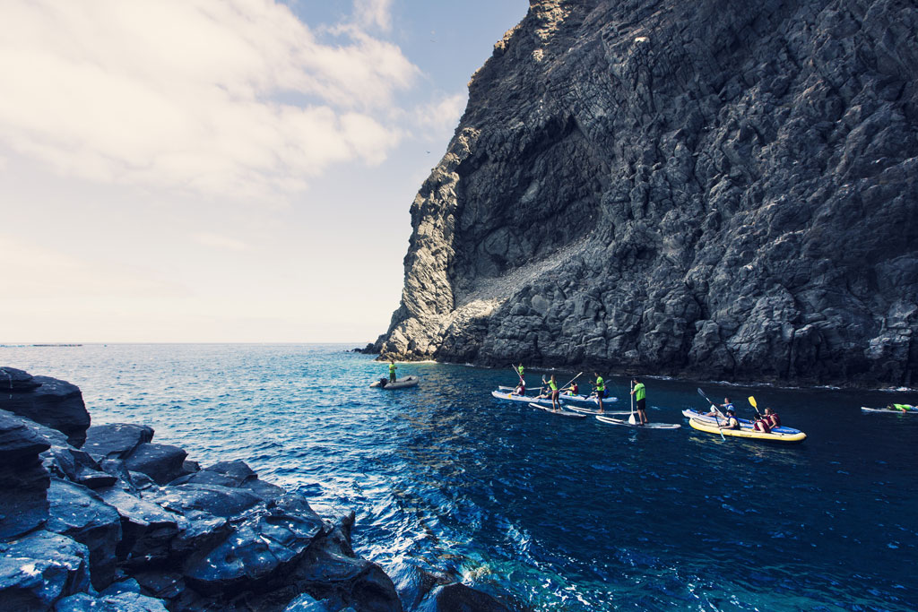 Personas practicando paddle surf cerca de un acantilado en Tenerife.