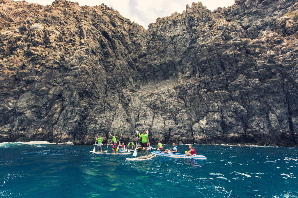 Personas practicando paddle surf frente a acantilados en Tenerife.