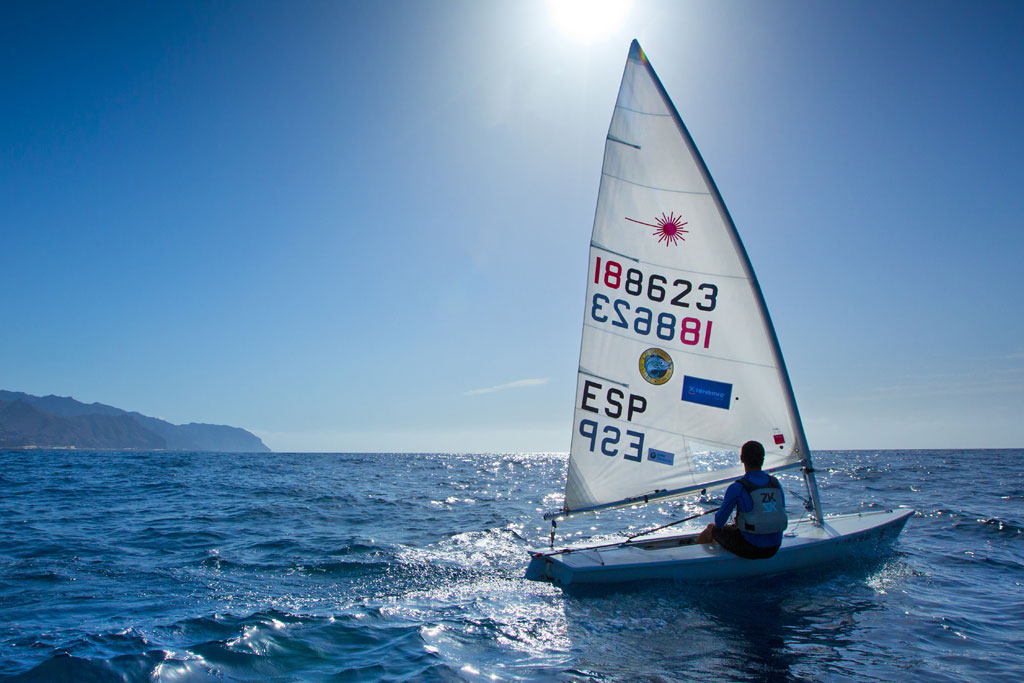 Persona navegando en un velero sobre el mar en Tenerife bajo un cielo soleado.